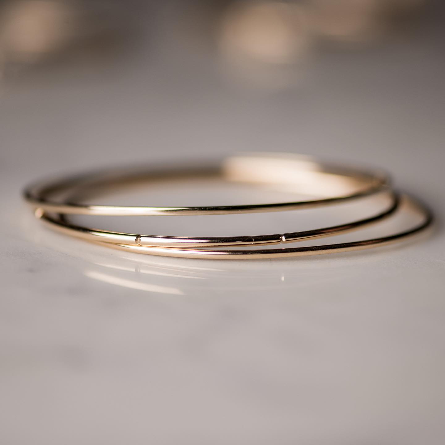 From our handmade bangle collection: our Petite Bangles, shown plain and grooved. Styled 14k yellow gold, also available