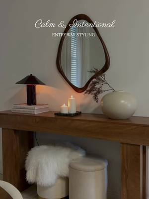 Calm & intentional. A small mirror to pause + reflect, a warm wood table with sleek lines, two tucked-away ottomans for 